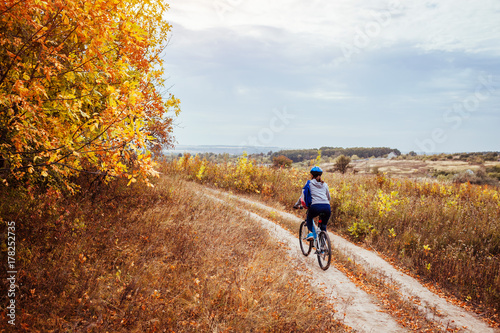 Young woman riding a bicycle in the autumn field
