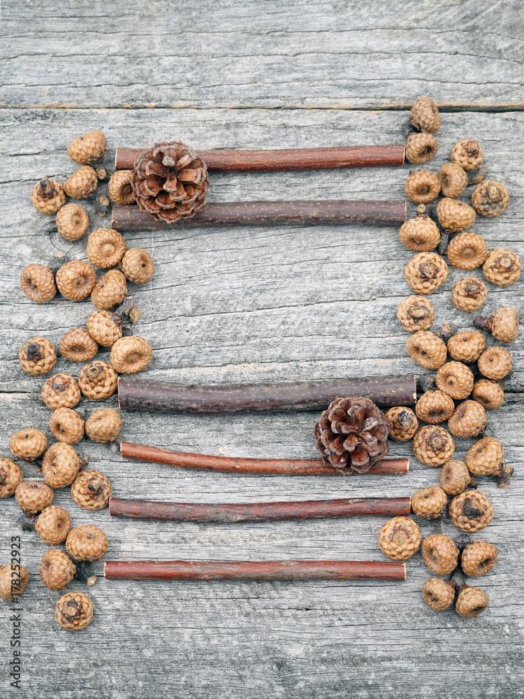 Still life composition/ frame with tiny acorns and wooden sticks on an old wooden surface. Beautiful vintage composition