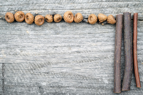 Still life composition/ frame with tiny acorns and wooden sticks on an old wooden surface. Beautiful vintage composition