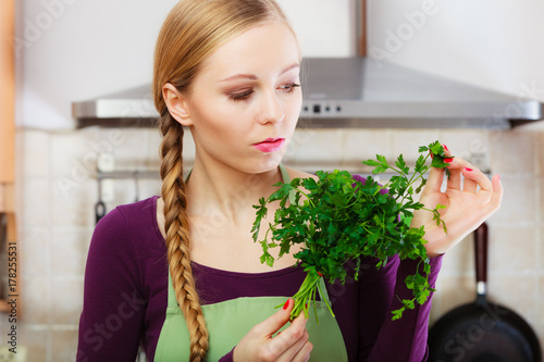 Woman in kitchen holds green aromatic parsley