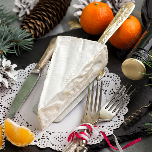 Brie cheese Cutlery fork and knife ,branches of fir, tangerines,