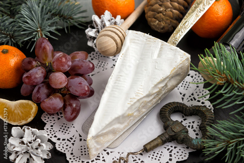 Brie cheese grapes branches, fir cones mandarins wine bottle cor