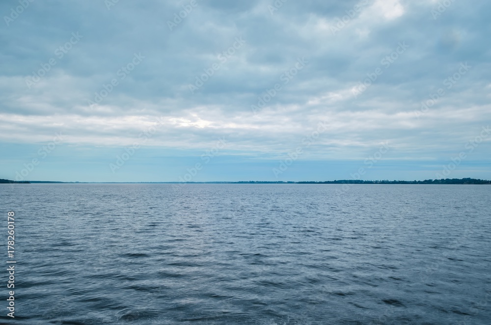 Minimalist summer landscape. Large lake with coastline on a cloudy day.