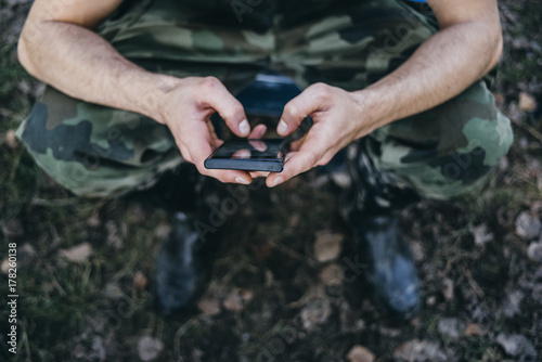 Man dressed in military clothes holding phone photo