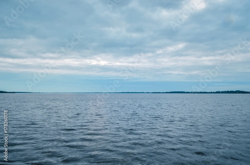 Minimalist summer landscape. Large lake with coastline on a cloudy day. © shadowmoon30