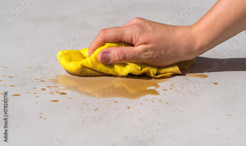 woman's hand cleaning tea stain or spilled coffee on a cement floor with a yellow floor cloth dishcloth closeup