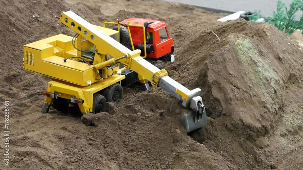 Digger excavator machinery digging action in construction site. Miniature model. Digger excavator machinery digging action in construction site. Miniature model.