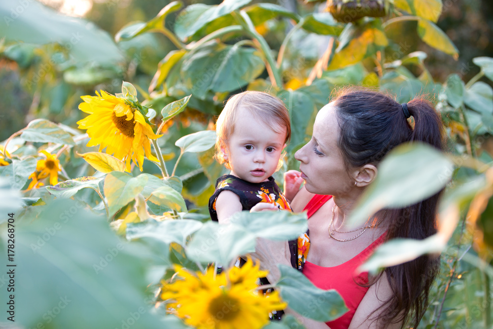 Mother with child in a field of sunflowers on a summer evening Mother with child in a field of sunflowers on a summer evening