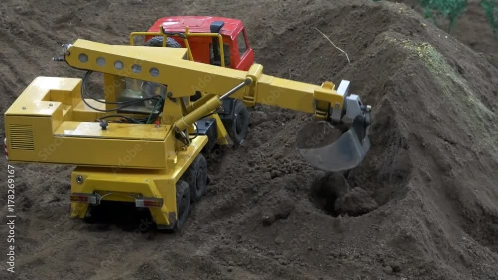 Backhoe excavator machinery digging and working on construction site. Miniature model.