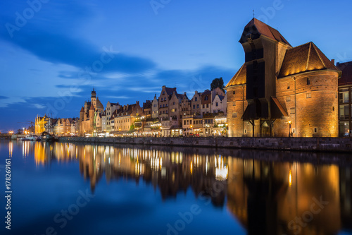 Scenic view of the lit Crane and other old buildings along the Long Bridge waterfront at the Main Town in Gdansk, Poland, in the evening.