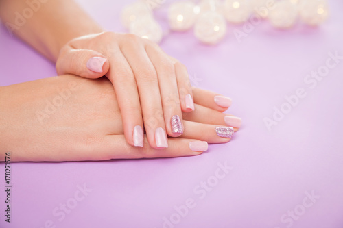 Beautiful pink and brilliant manicure on purple background
