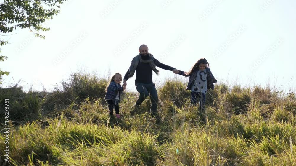 Father with his two daughters running from the hill at camera. Father with his two daughters running from the hill at camera.