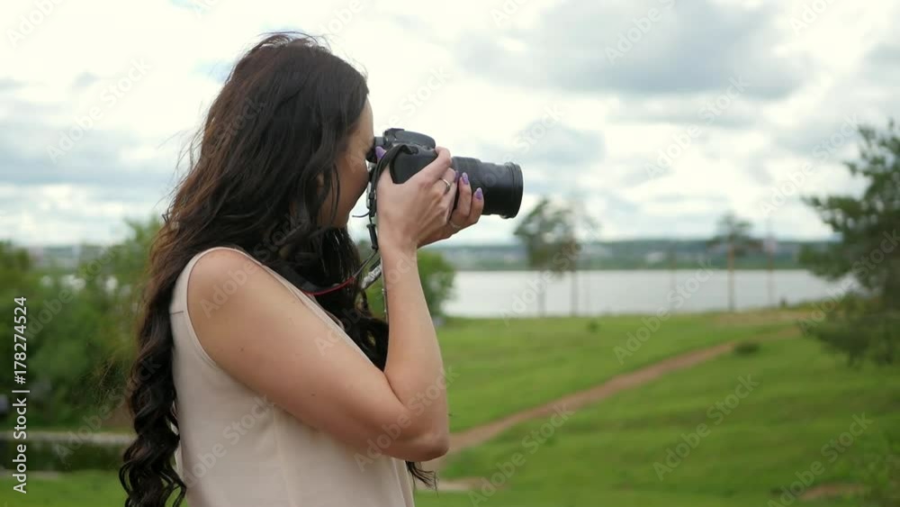 Beautiful woman takes photos of nature on big professional camera Beautiful woman takes photos of nature on big professional camera