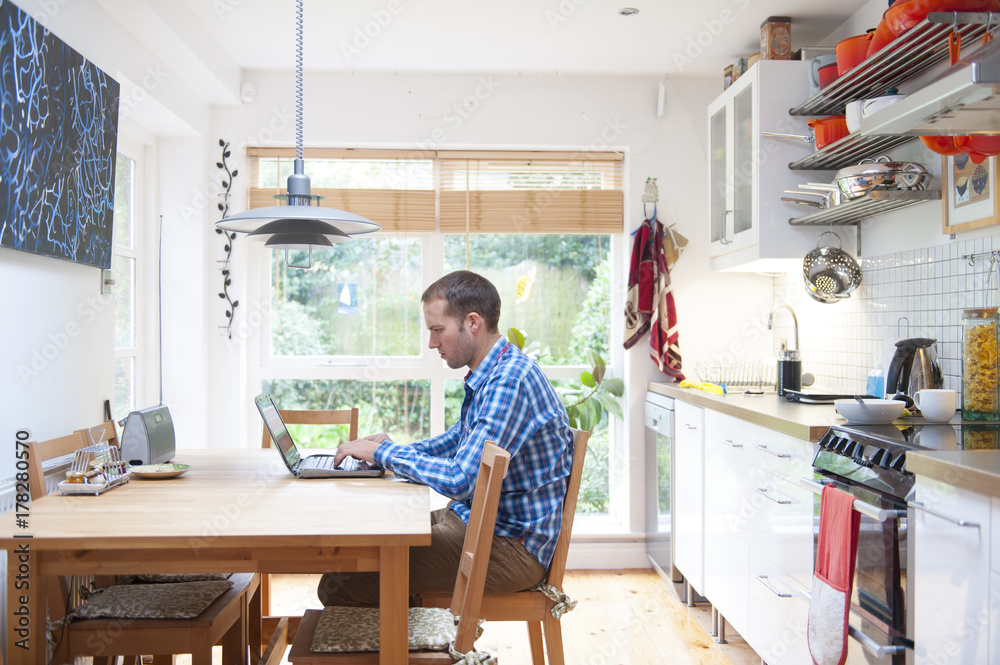 man working at a laptop in the kitchen man working at a laptop in the kitchen