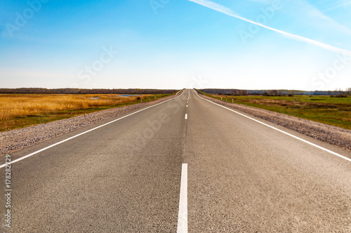 The picturesque landscape and the Sunrise over the road. Asphalt road with marking. With the blur and bright sunlight