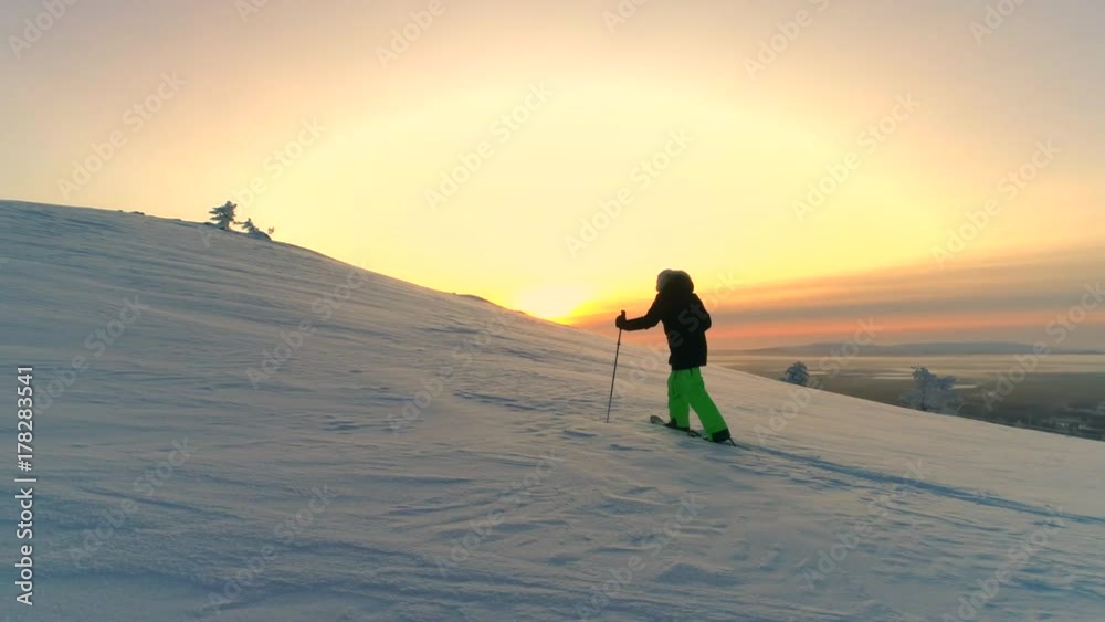 AERIAL Active woman in winter clothes snowshoeing on snowy mountain slope at sunrise. Young woman snowshoe hiking at winter sunset. Traveler snowshoe exploring snowy Lapland mountains in sunny morning AERIAL Active woman in winter clothes snowshoeing on snowy mountain slope at sunrise. Young woman snowshoe hiking at winter sunset. Traveler snowshoe exploring snowy Lapland mountains in sunny morning