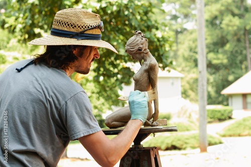 artist applying patina to sculpture photo
