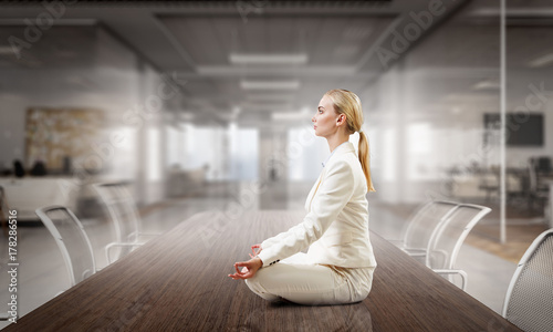 Business lady meditating at work. Mixed media