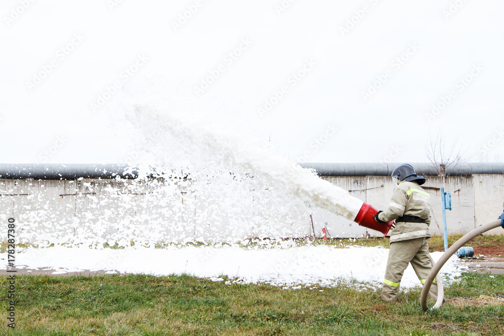 Fototapeta premium Firefighters extinguish the fire with a chemical foam coming from the fire engine through a hose