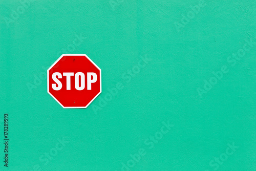 Image of a bright red stop sign against a vibrant green wall