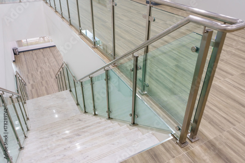 Murais de parede Modern white marble stairs with steel and glass railing in a new modern building