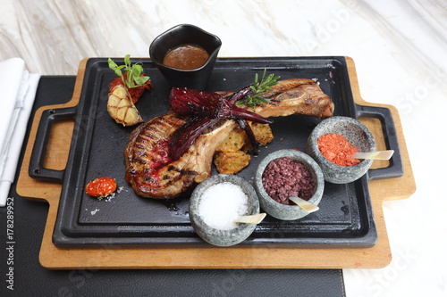 Pork Chop with three kind of salt and sauce, on heat plate wooden under, American Style Luxury Restuarant photo