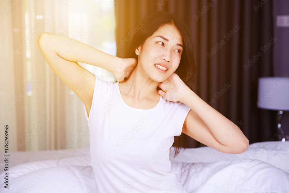 Woman waking up and hand raised on bed in bedroom Woman waking up and hand raised on bed in bedroom