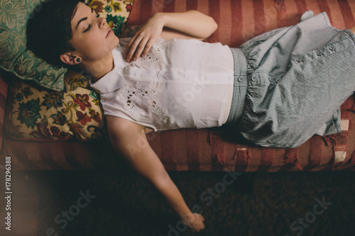 Beautiful girl lying on old couch with pillows photo