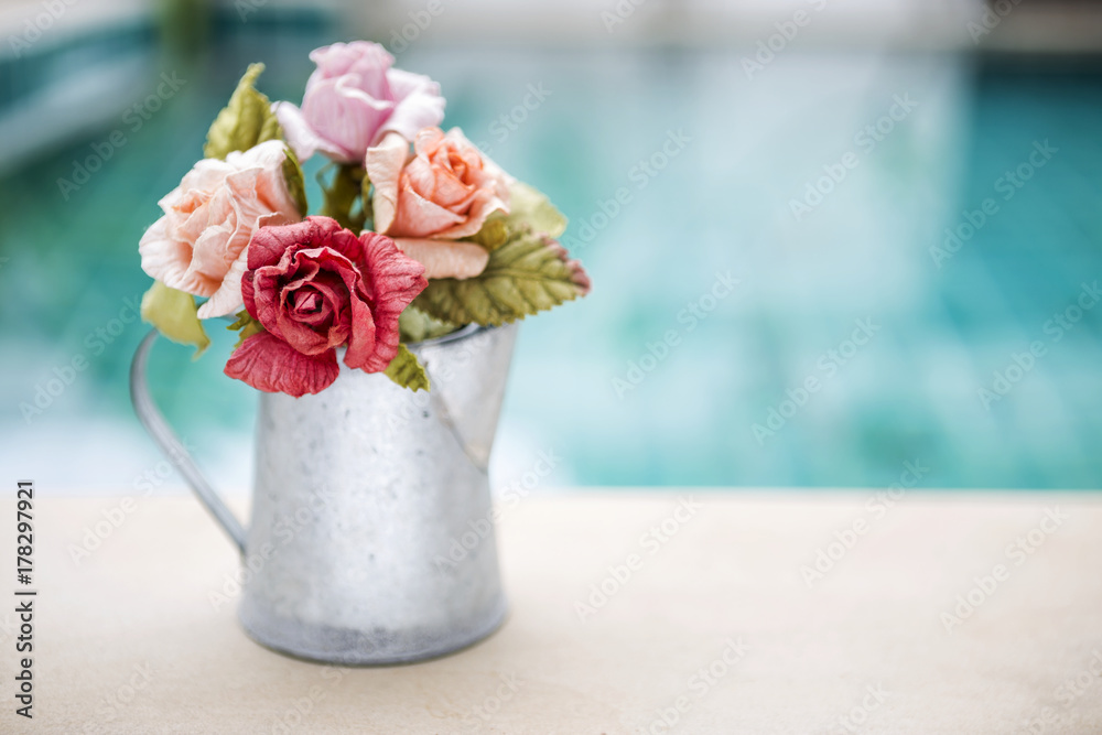 Rose paper in tin water pot with space on blurred blue background, outdoor day light Rose paper in tin water pot with space on blurred blue background, outdoor day light
