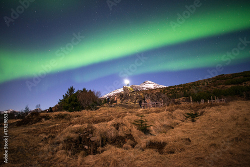 The beautiful Aurora trails (Northern lights) over the snowcap mountain in the countryside of Iceland.