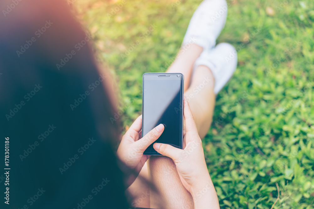 Beautiful Young asian woman smiling while reading her smartphone in garden. Portrait of asian women reading message with smart phone in park outdoor.