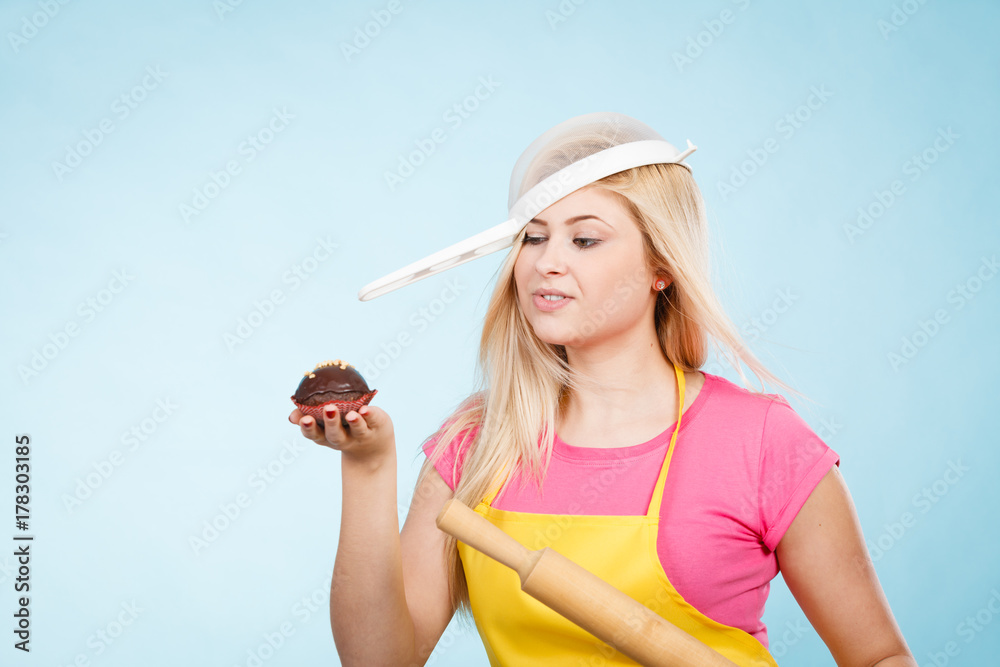 Woman holding cupcake, rolling pin wearing colander on head Woman holding cupcake, rolling pin wearing colander on head