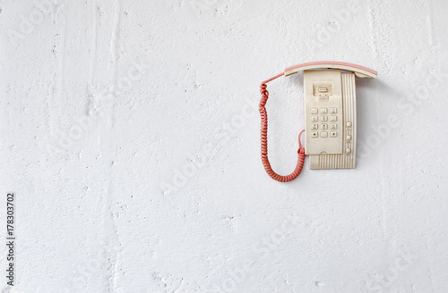 Dead telephone hanging on white wall