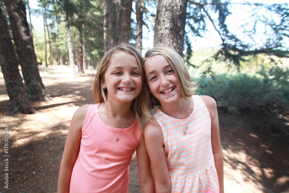 Portrait of happy twin sisters in a forest Portrait of happy twin sisters in a forest