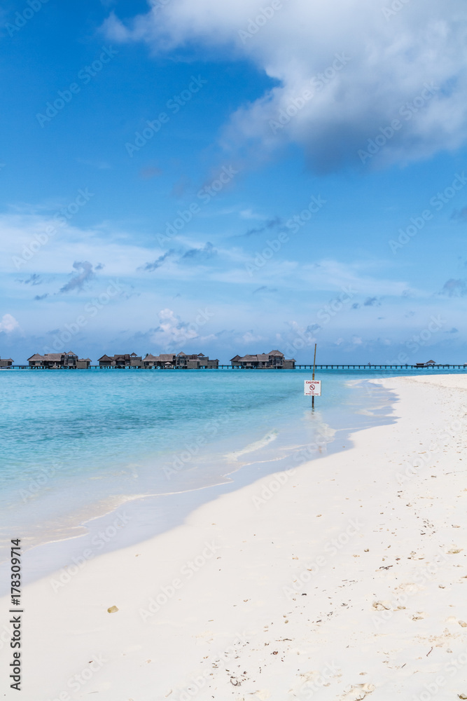 paradisiac beach on the maledives with a warning sign paradisiac beach on the maledives with a warning sign