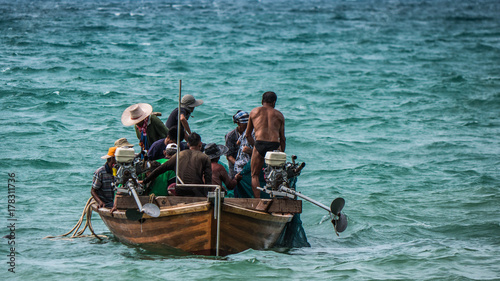The fishermen on the fishing boat working together to harvest the fish from the sea with the fishing net