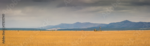 Classic African Farm Scene: dry fallow pasture with the blue mountains in the background. A water pump windmill in the landscape.