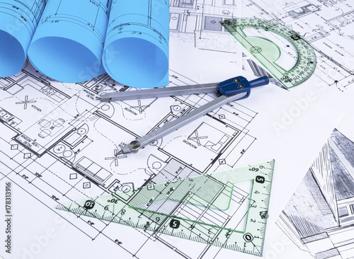 Architectural blueprints and blueprint rolls and a drawing instruments on the worktable. Drawing compass, plans. Civil Engineering, Construction background.