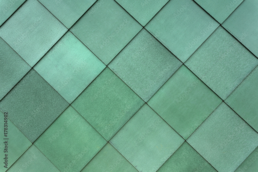 Square green cladding fastened to the exterior of a building to form a pattern Square green cladding fastened to the exterior of a building to form a pattern