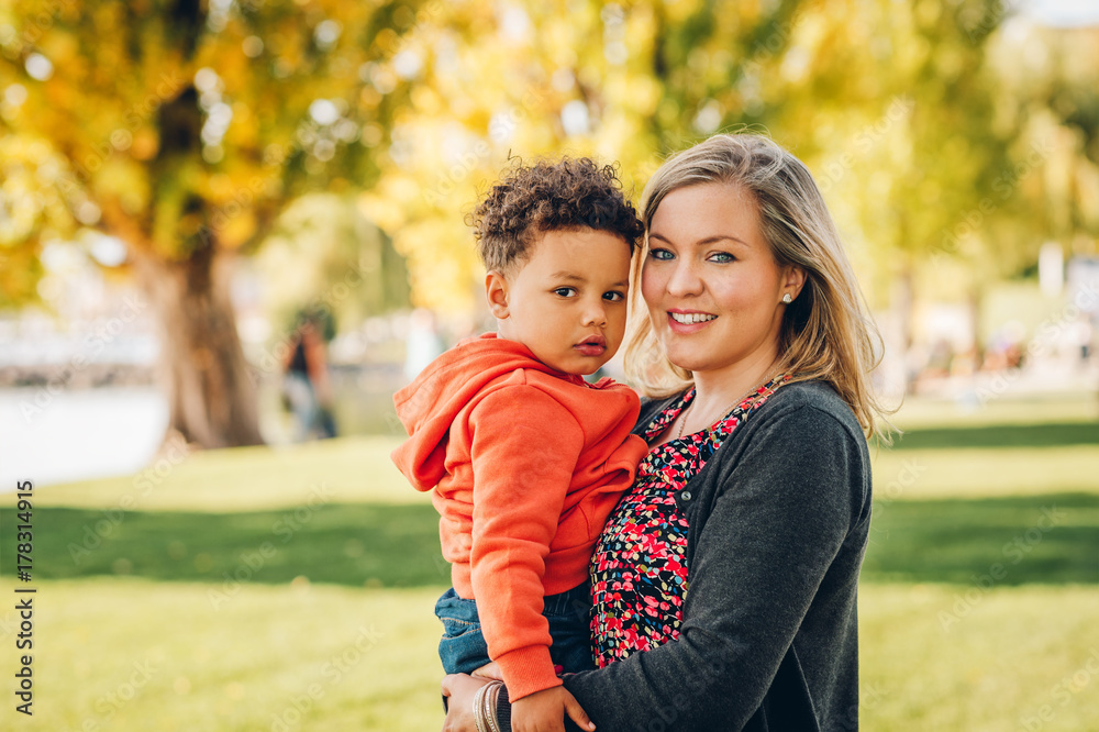 Happy young mother holding sweet toddler boy, family having fun together outside on a nice sunny day Happy young mother holding sweet toddler boy, family having fun together outside on a nice sunny day