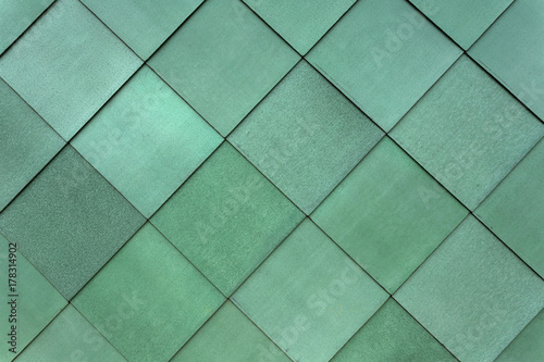 Square green cladding fastened to the exterior of a building to form a pattern