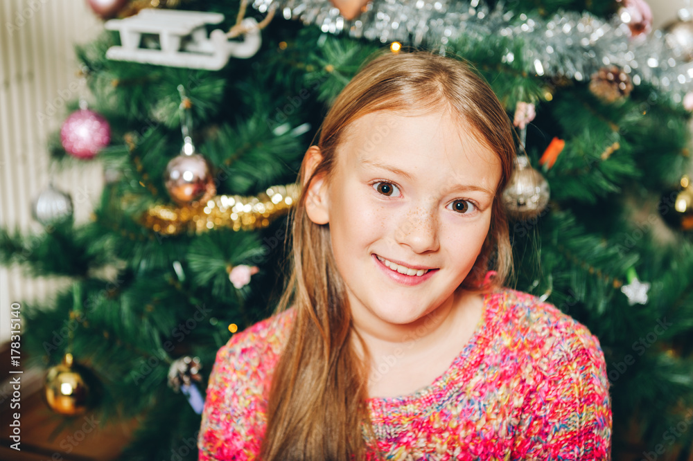 Close up portrait of happy preteen girl playing next to christmas tree Close up portrait of happy preteen girl playing next to christmas tree