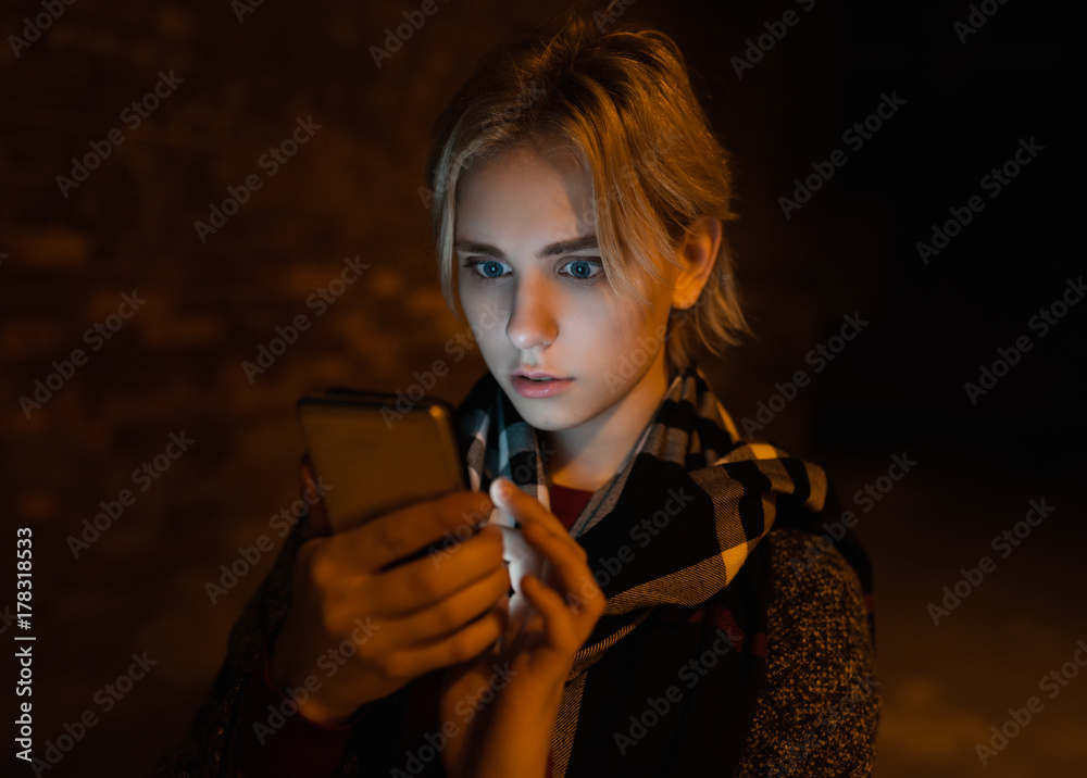 Young woman using smartphone on the street by night. Young woman using smartphone on the street by night.