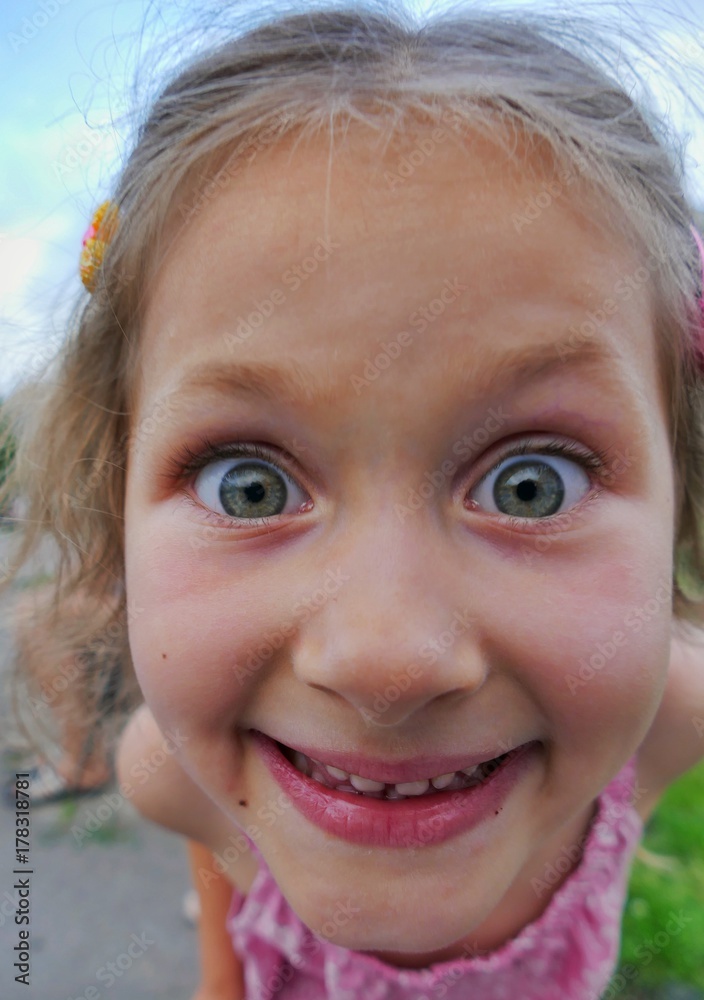 Close-up portrait of a naughty funny little girl who looks with interest at the camera lens Close-up portrait of a naughty funny little girl who looks with interest at the camera lens