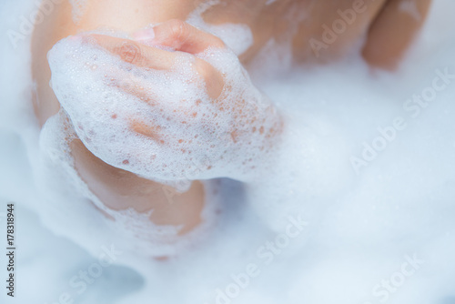 Young woman taking a relaxing bath with foam