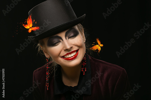 Girl in hat with bright make-up on Halloween in the studio. Heavenly girl. Girl with earrings. witch