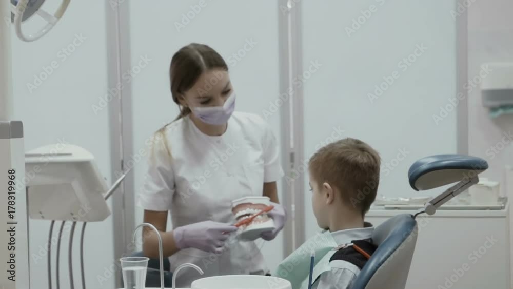 Stomatologist shows a little boy how to clean teeth with toothbrush ...