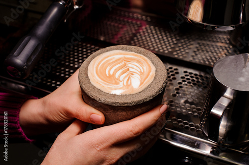 Woman hands holding a concrete pot with latte