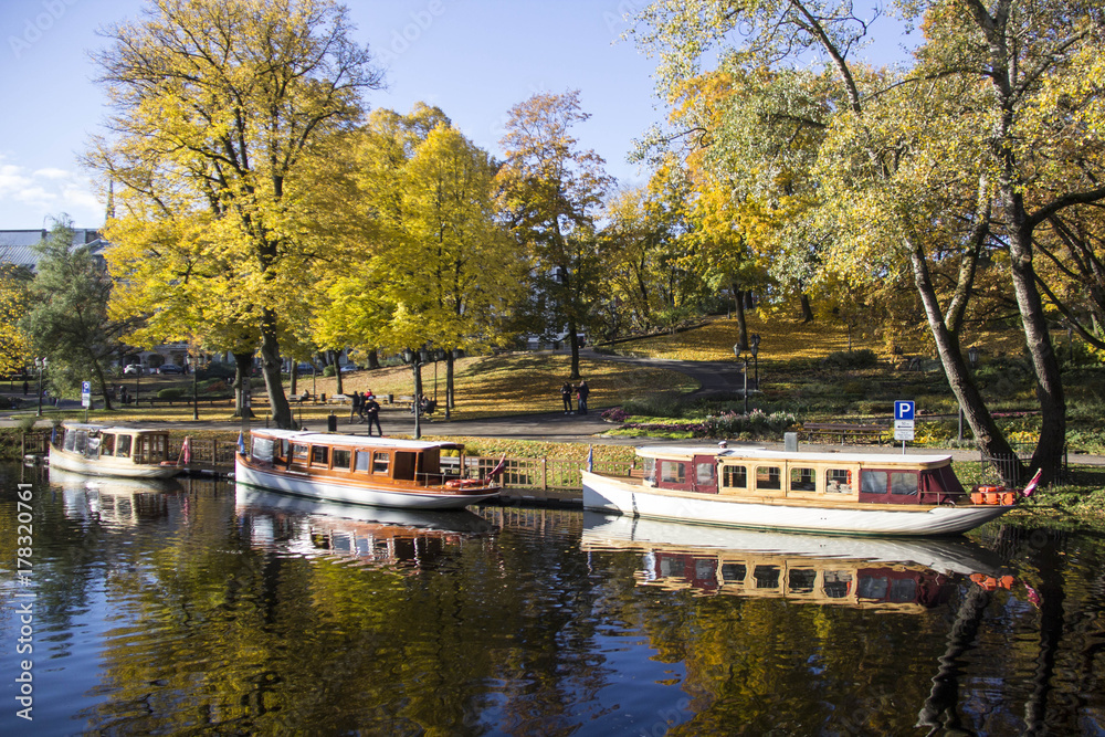 tourist boats Autumn park in the center of Riga, Latvia Canal that flows through Bastion park autumn background with colored leaves (Bastejkalns).. Famous tourist place in Baltic region