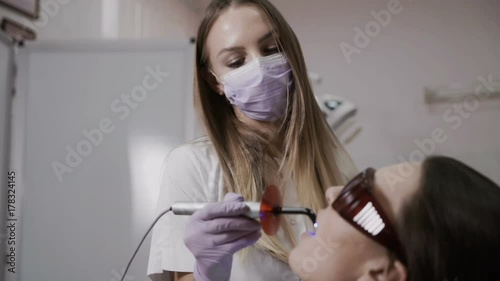 Dentist makes a procedure with a dental polymerization lamp to a patient photo
